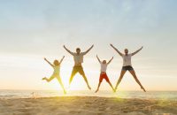 Family doing star jumps on beach